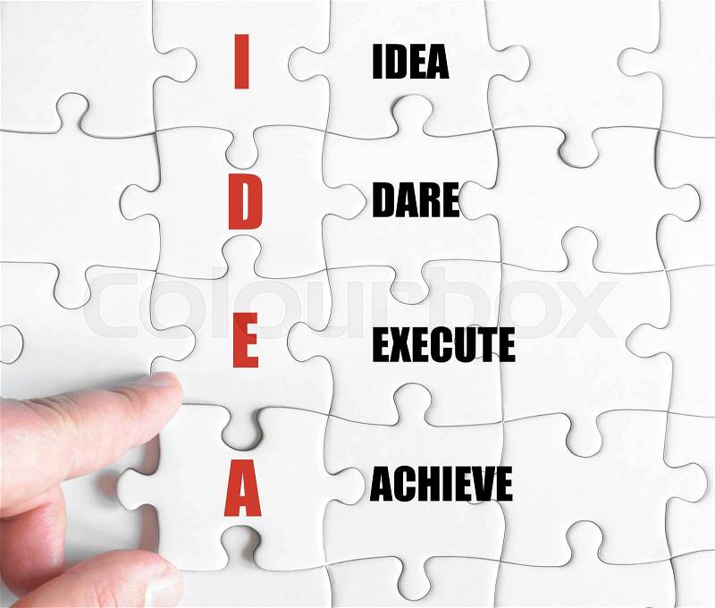 Hand of a business man completing the puzzle with the last missing piece.Concept image of Business Acronym IDEA as Idea Dare Execute Achieve, stock photo