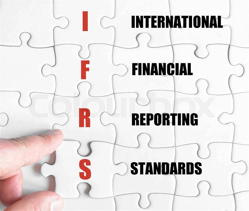 Hand of a business man completing the puzzle with the last missing piece.Concept image of Business Acronym IFRS as International Financial Reporting Standards, stock photo