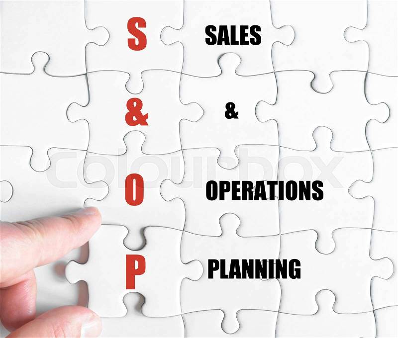 Hand of a business man completing the puzzle with the last missing piece.Concept image of Business Acronym SOP as Sales And Operations Planning, stock photo