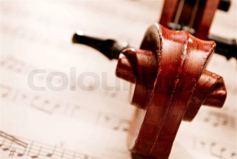 High Angle View Close Up of Carved Wooden Violin Scroll Resting on Top of Sheet Music Composition, Musical Still Life with Copy Space, stock photo