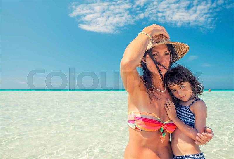 Mother and daughter together embracing in the ocean turquoise water, stock photo