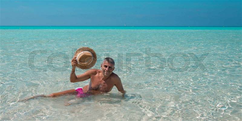 Man with straw hat relaxing on turquoise water, stock photo