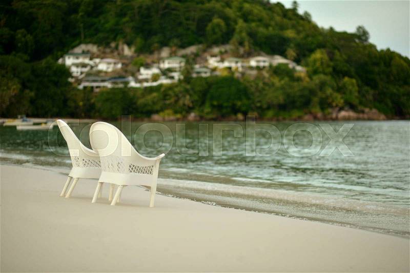 Two empty white chairs at the tranquil beach, stock photo