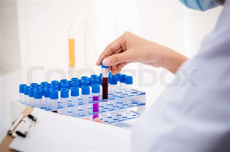 Close up of scientist recording and examining chemical tubs in lab, stock photo