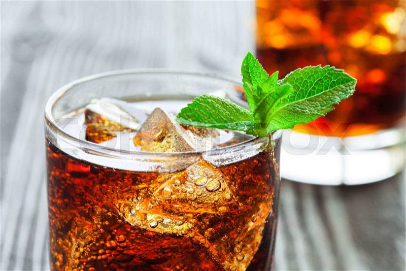 Two glasses of cola with ice and fresh mint on a beautiful wooden table, stock photo
