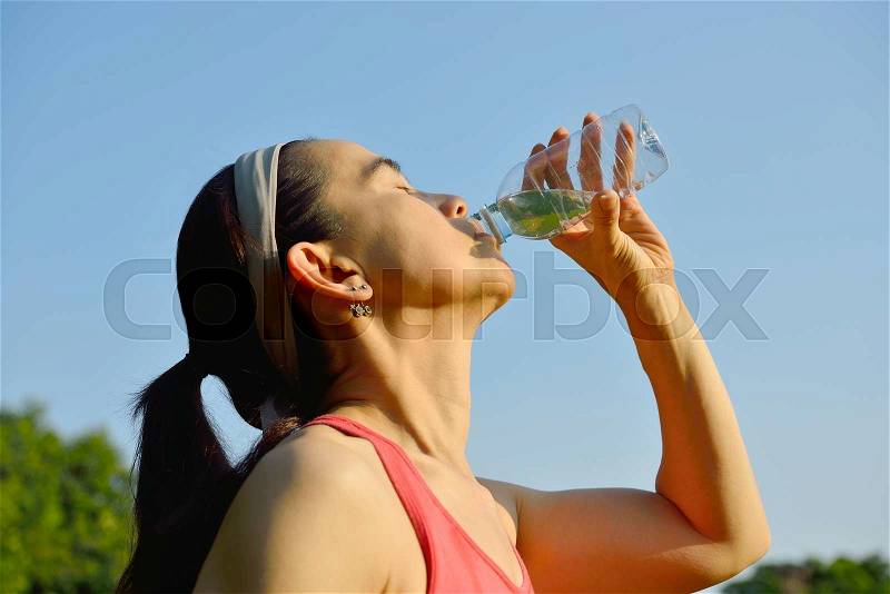Middle aged woman drinking water after exercising, stock photo