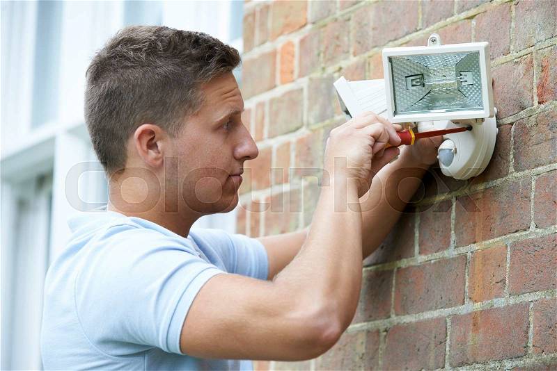 Security Consultant Fitting Security Light To House Wall, stock photo