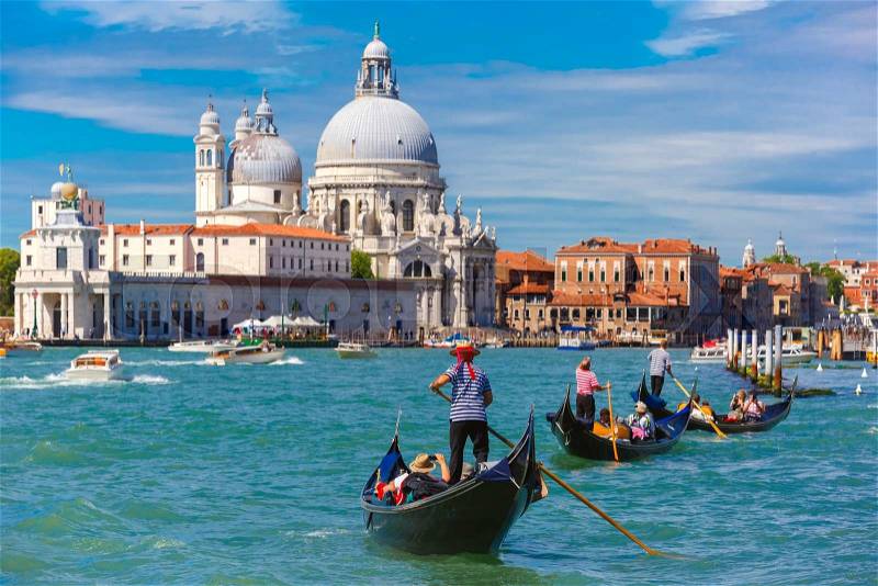Picturesque view of Gondolas on Canal Grande with Basilica di Santa Maria della Salute in the background, Venice, Italy. Selective focus on Gondolier, stock photo