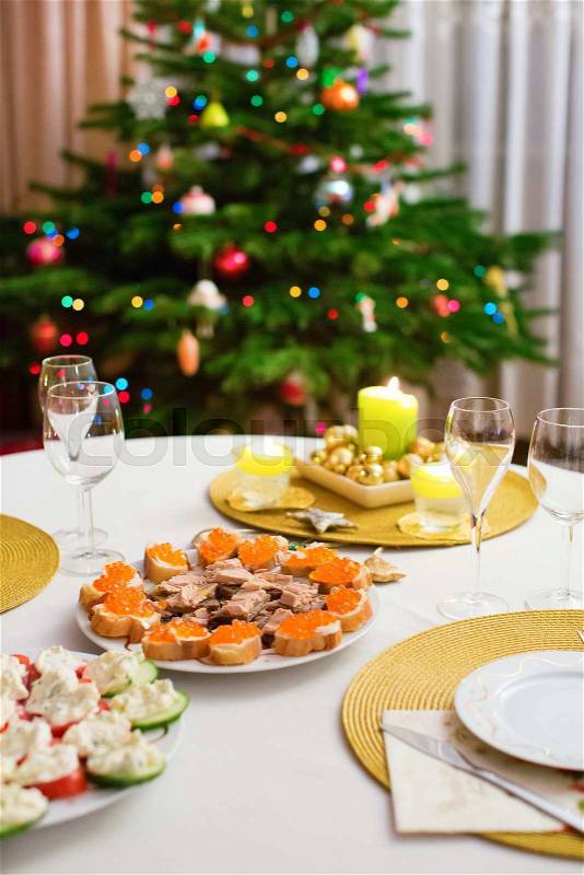Decorated Christmas dining table with Christmas tree in background, stock photo