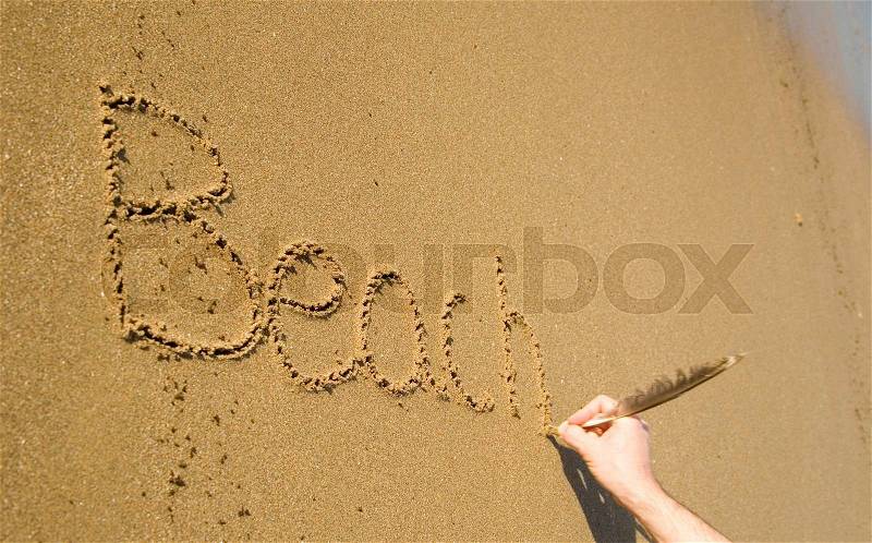Word Beach written on the sand. Focus on letters, stock photo