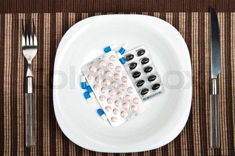 Pills on plate with fork and knife, stock photo