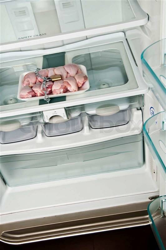 Refrigerator close up with locked chicken leg, stock photo