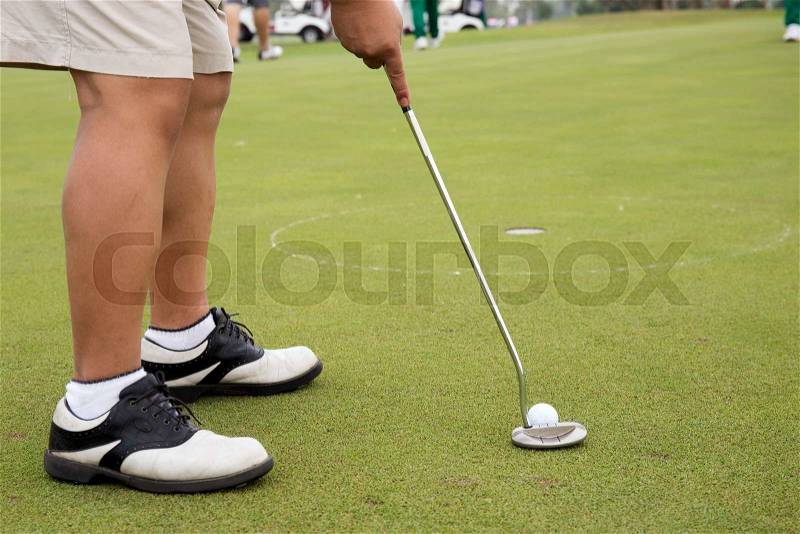 Close up Golf player putting ball in to hole, stock photo