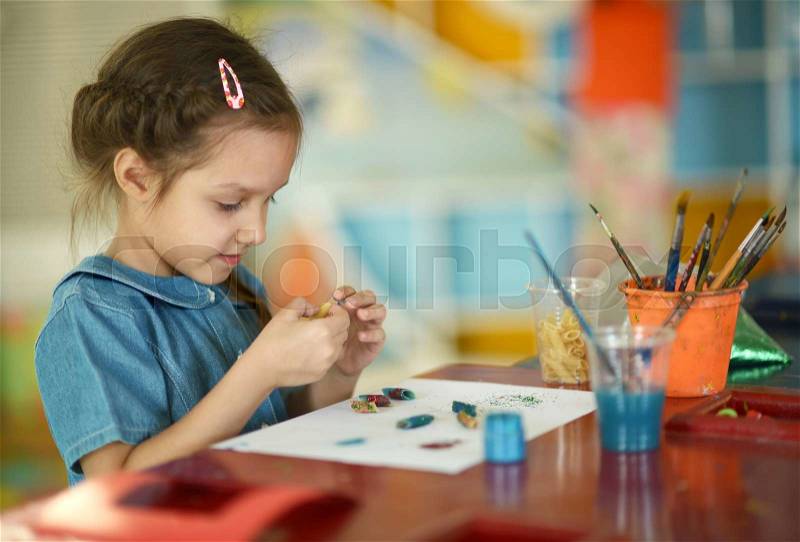 Little girl drawing with paints at home, stock photo