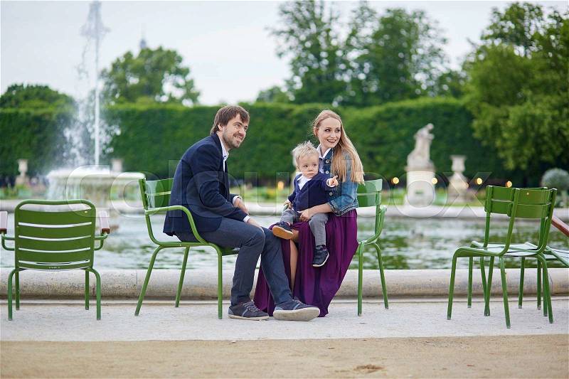 Happy family of three in the beautiful garden of Palais Royal in Paris on a summer day, stock photo