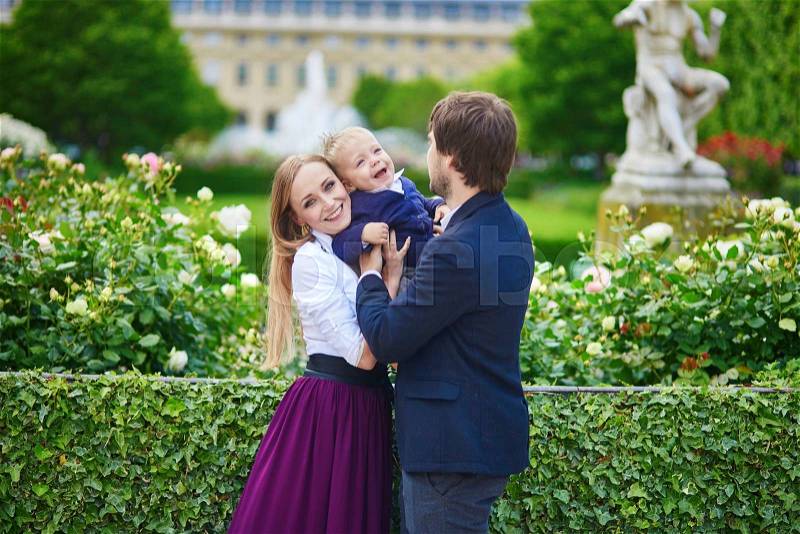 Happy family of three in the beautiful garden of Palais Royal in Paris on a summer day, stock photo