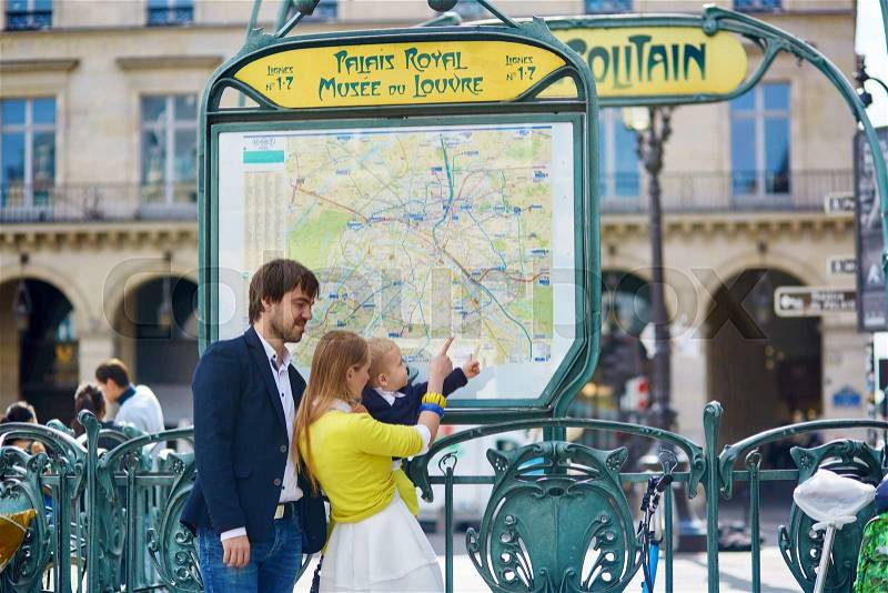 Family of three in Paris, looking at the Parisian subway map, stock photo