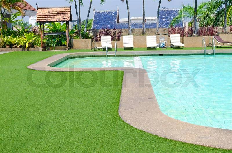 Swimming pool with green grass and palm at hotel close up , stock photo