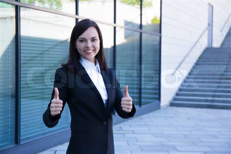 Career concept - young business woman thumbs up over modern city background, stock photo