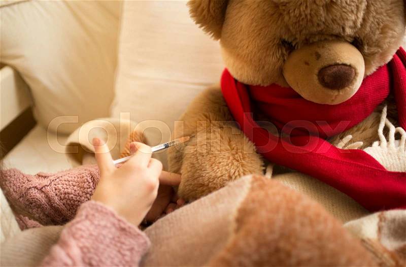 Closeup photo of little girl doing injection to sick teddy bear, stock photo