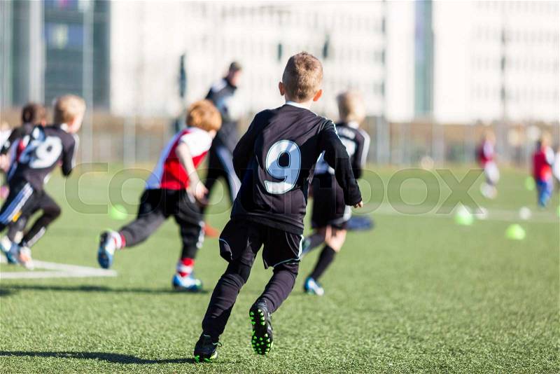 Young kids playing a soccer training match outdoors on an artificial soccer pitch, stock photo