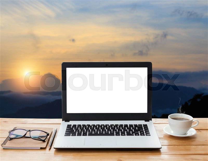 Laptop computer and coffee on wood workspace and mountain at sunset background, stock photo
