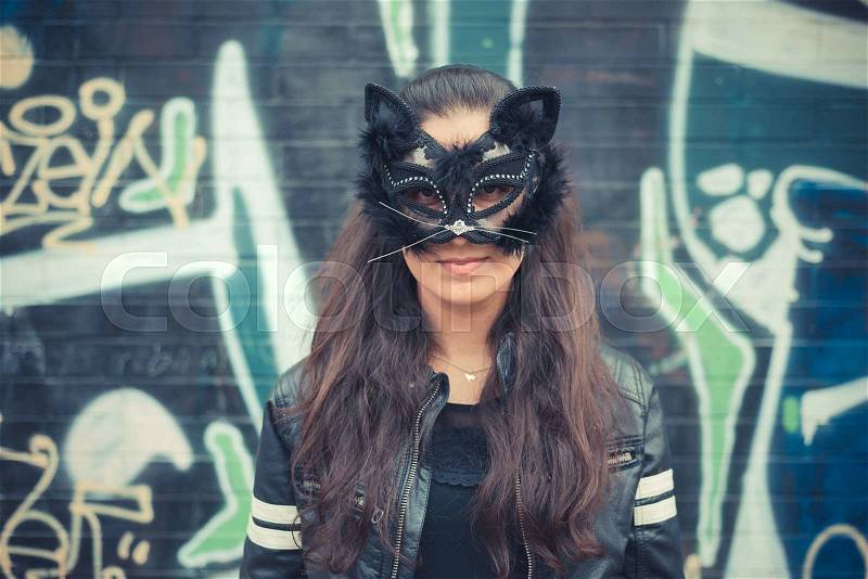 Cat mask young beautiful brunette woman in the city, stock photo