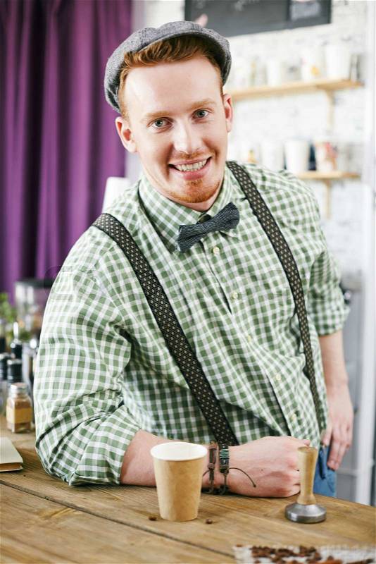 Happy barista looking at camera in cafe, stock photo