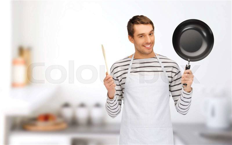 People, cooking and culinary concept - happy man or cook in apron with frying pan and wooden spoon over home kitchen background, stock photo
