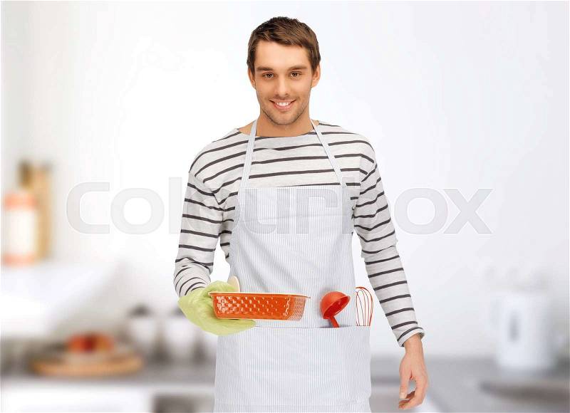 People, cooking, culinary and food concept - happy man or cook in apron with baking and kitchenware over home kitchen background, stock photo