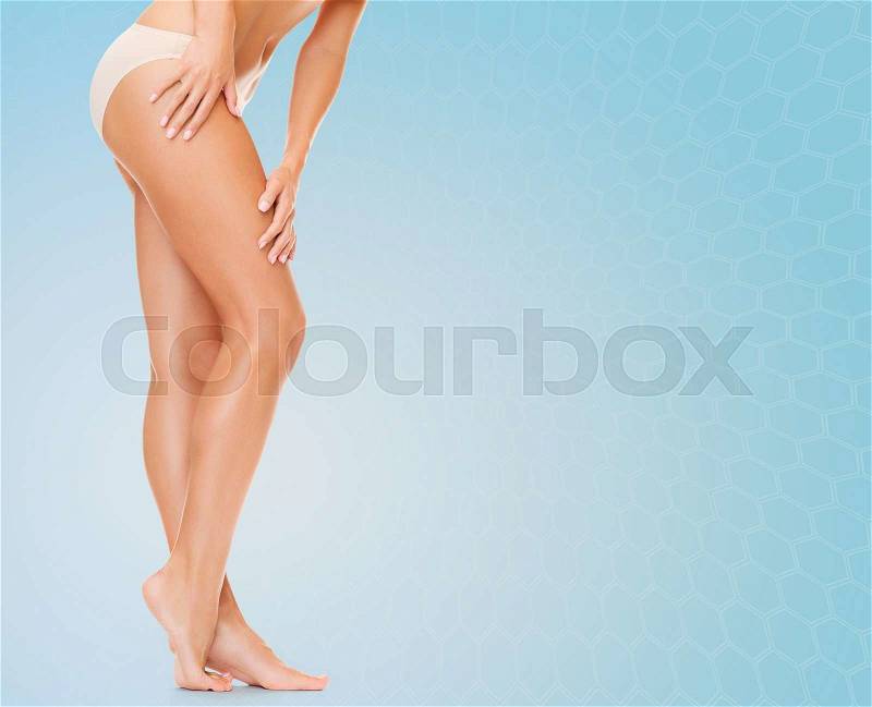 People, health and beauty concept - woman with long legs in cotton panties touching her hips over blue background, stock photo