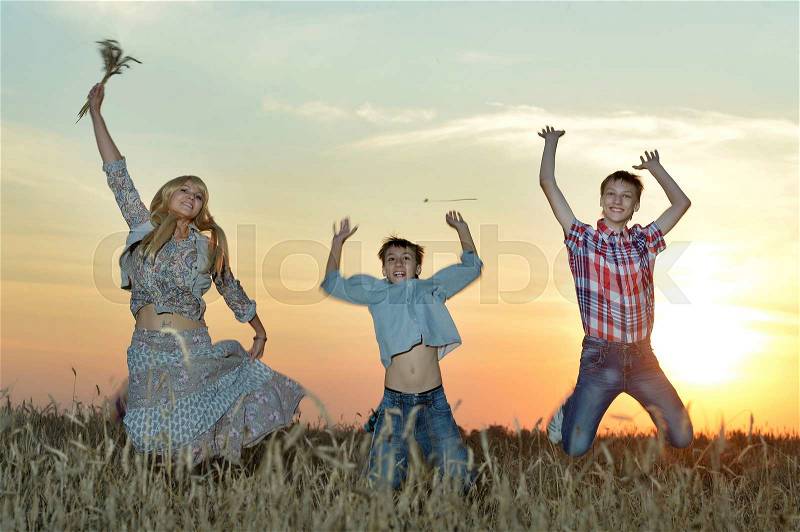 Mom with with her children on wheat field at a picnic on sunset, stock photo
