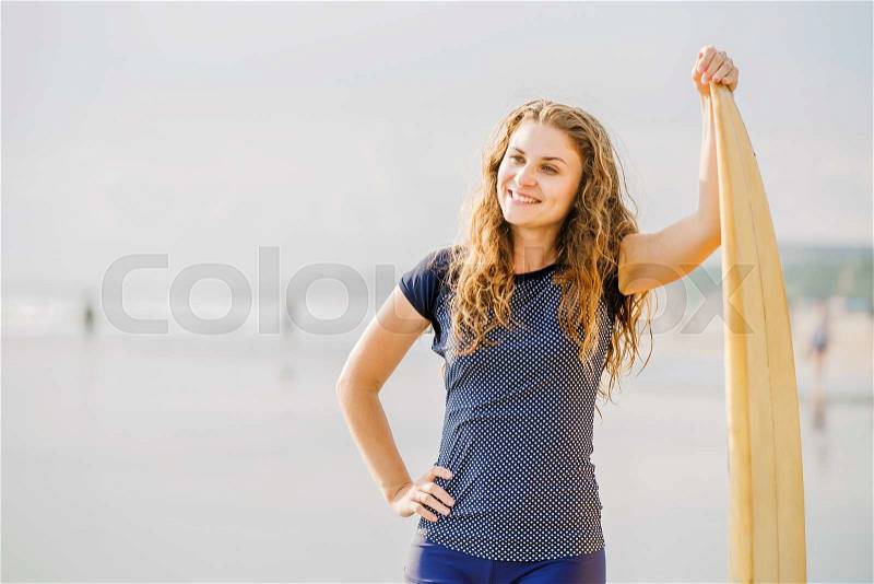 Beautiful young surfer girl stays on the beach at sunset light with yellow surfboard. Healthy lifestyle, leisure, travel, holiday and sport concept, copyspace, stock photo