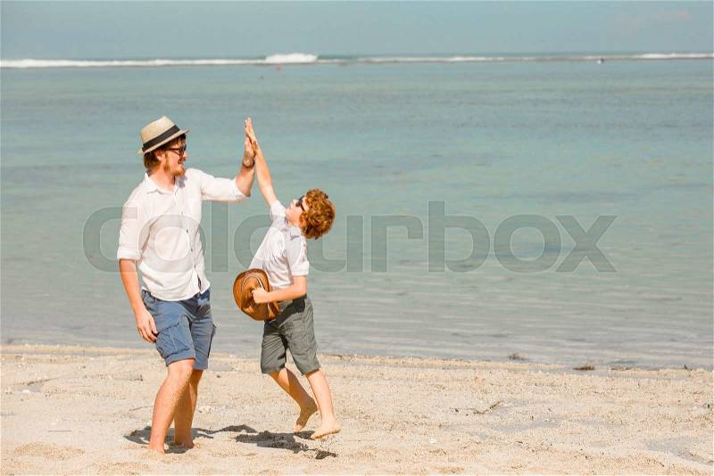 Hipster father with beard and red haired son playing on the beach at the summer day. Vacation, happy and friendly family, holidays concept, stock photo
