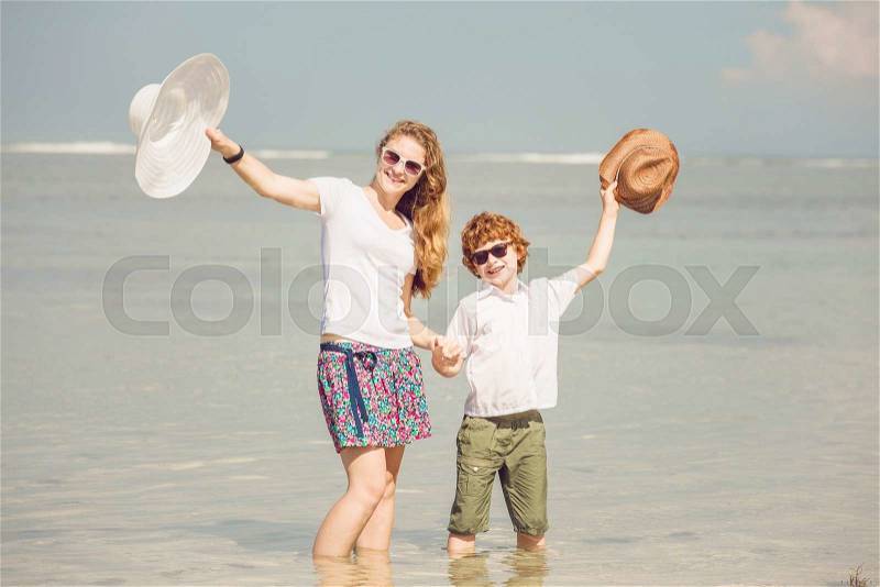 Mother and red haired son having family time on holidays walking along the beach. Travel, holiday, vacation concept , stock photo