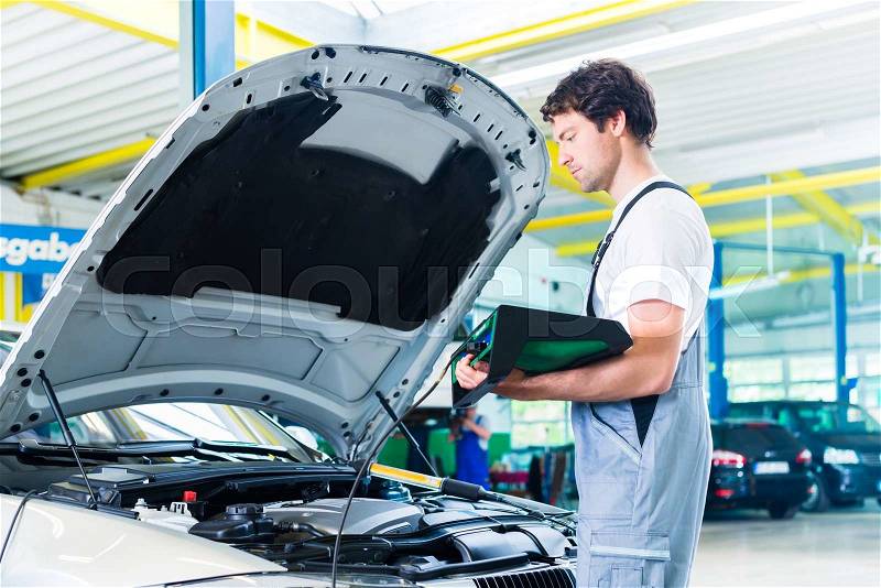 Mechanic with diagnostic tool in car workshop, stock photo