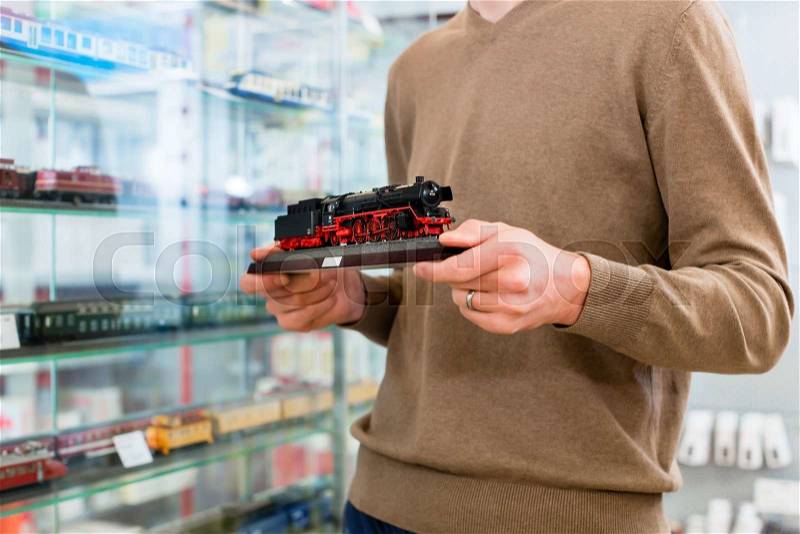 Man in toy store buying model railroad holding the model in his hands, stock photo
