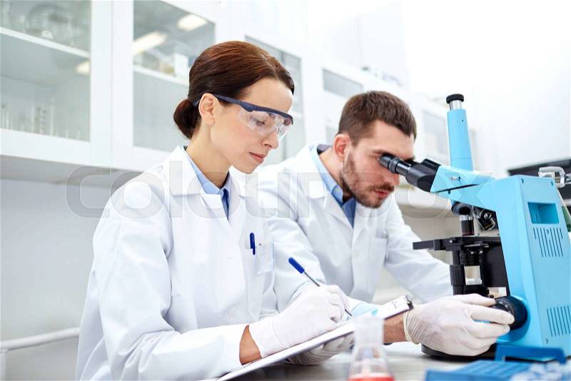 Science, chemistry, technology, biology and people concept - young scientists shaking glass with reagent and making test or research in clinical laboratory, stock photo