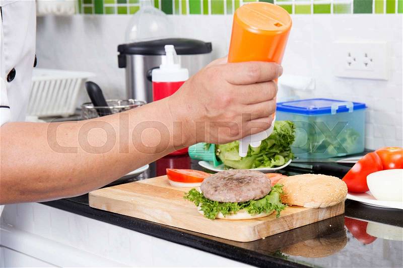Chef putting mayonnaise on the Hamburger bun /Cooking Hamburger concept, stock photo