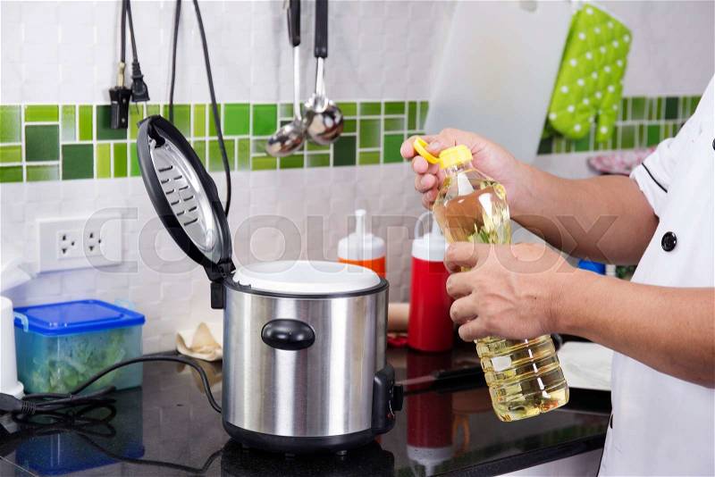 Chef open cap of vegetable oil bottle before cooking, stock photo