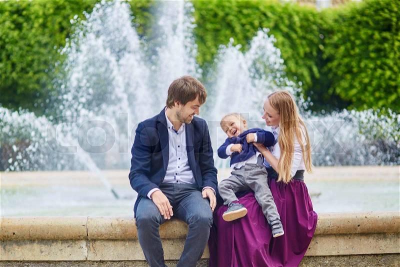 Happy family of three in the beautiful garden of Palais Royal in Paris, stock photo