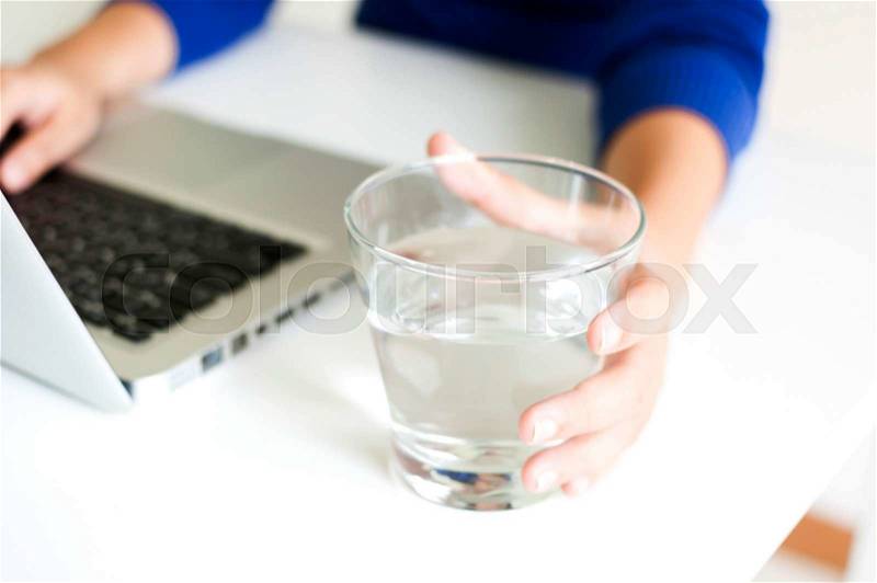 Drinking water while working with laptop computer, stock photo