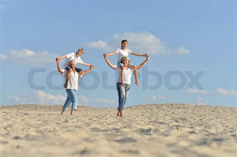 Funny boys with grandparents walking on the sand in the summer, stock photo