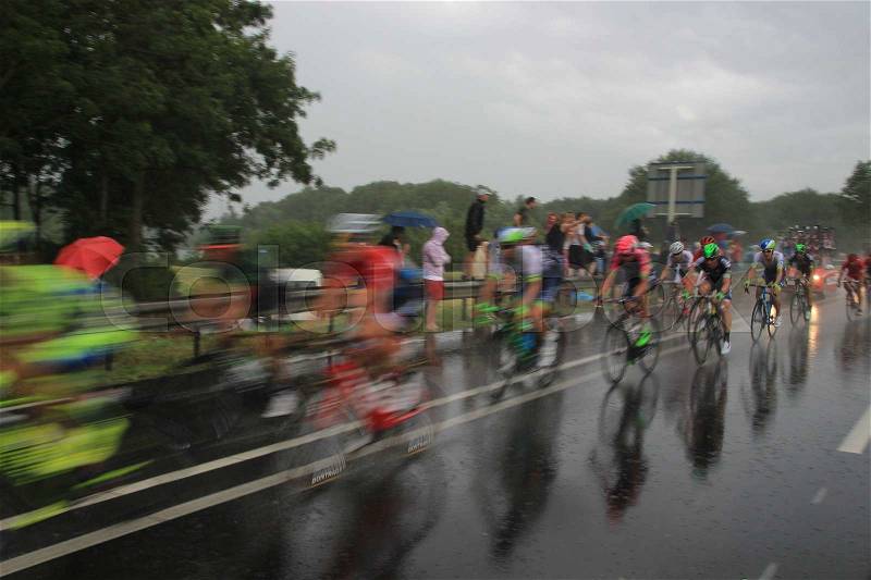The audience support the cyclists of the Tour de France in the bad wheater, it\'s raining cats and dogs, in the summer, stock photo