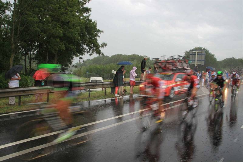The audience support the cyclists of the Tour de France in the bad wheater, it\'s raining cats and dogs, in the summer, stock photo