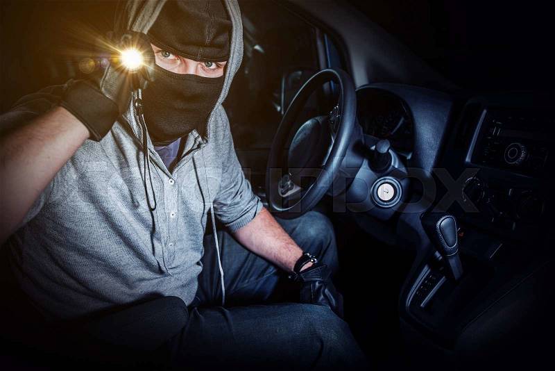 Car Thief with Flashlight Inside Stolen Car at Night. Car Insurance and Protection Concept, stock photo