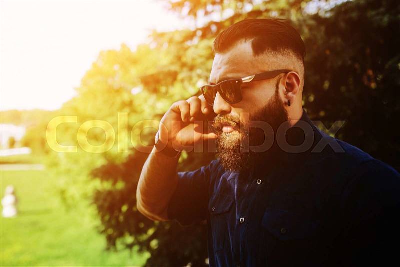 Bearded man stands on the street and speaks by phone, stock photo