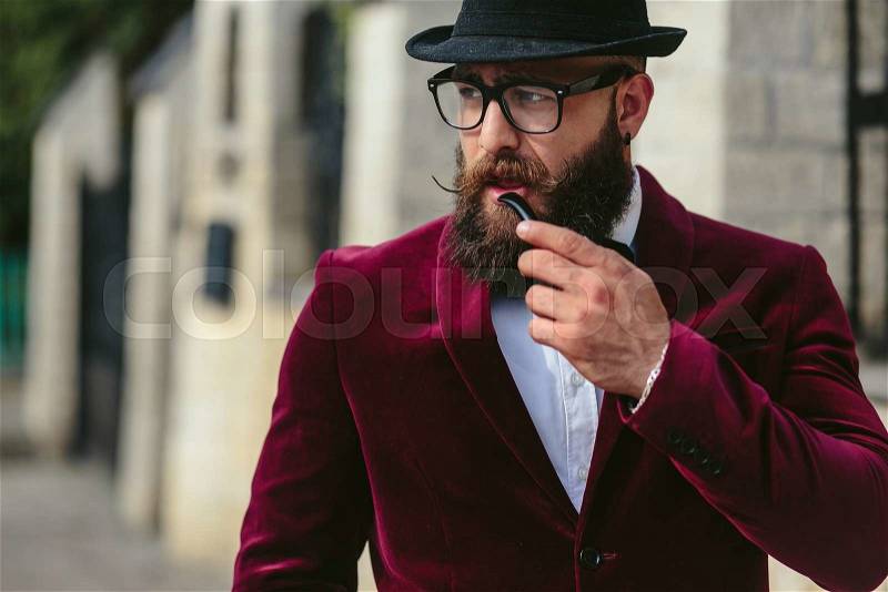 A rich man with a beard smokes electronic cigarette, stock photo