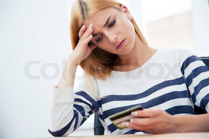 Unhappy casual woman holding bank card, stock photo