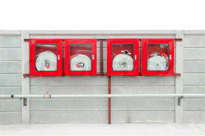 Emergency fire hose inside a glass fronted box mounted on a wall attached to a metal hydrant to provide water flow and pressure in an emergency, stock photo
